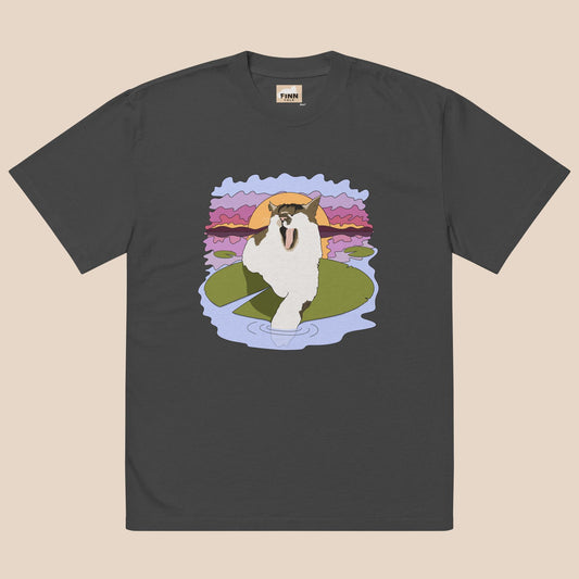 Black t-shirt with a cartoon cat on a lily pad design against a beige background