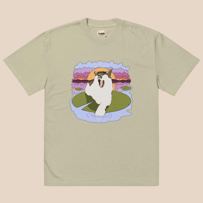 T-shirt with a graphic of a cat on a lily pad against a sunset background