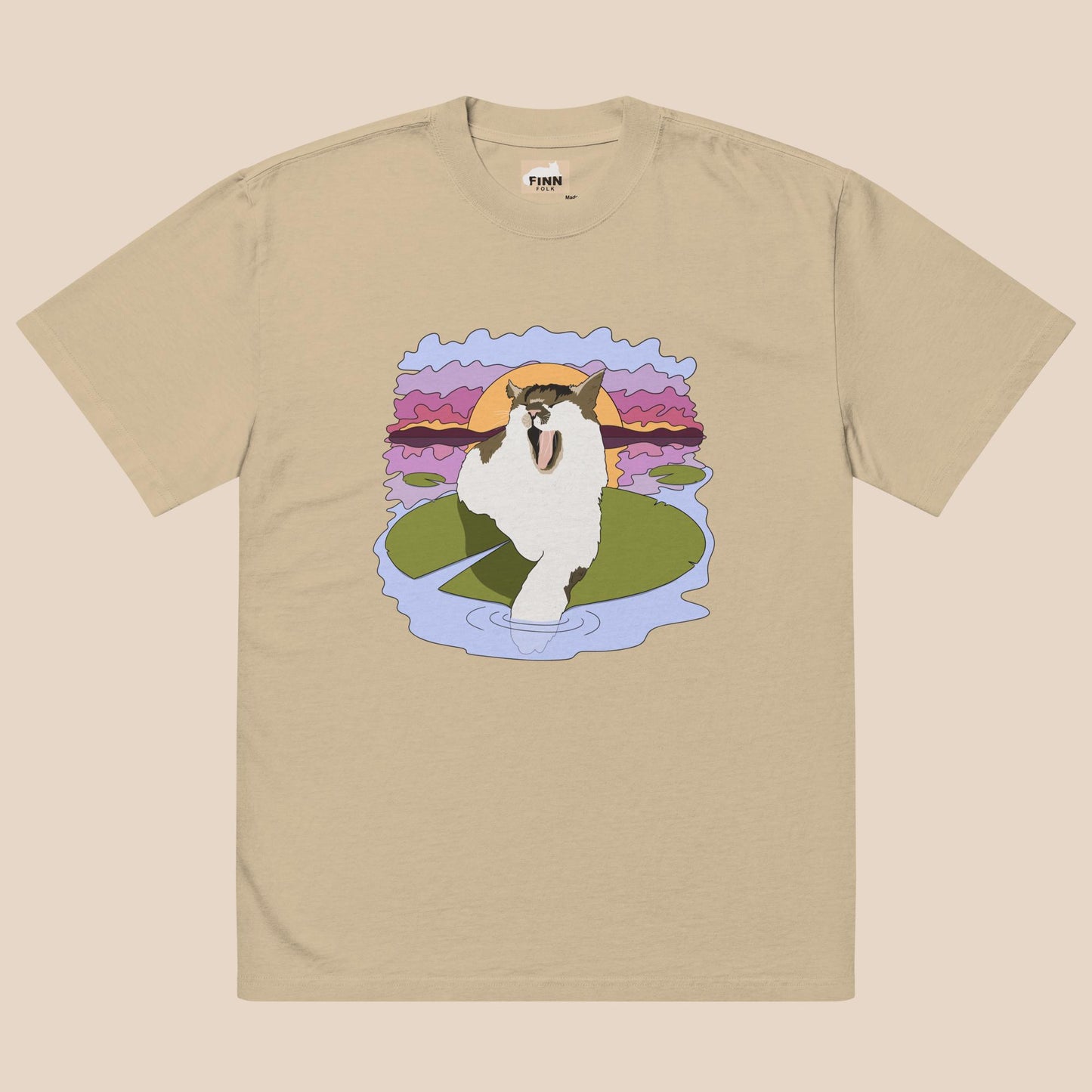 Beige t-shirt with a graphic of a cat on a lily pad against a sunset background